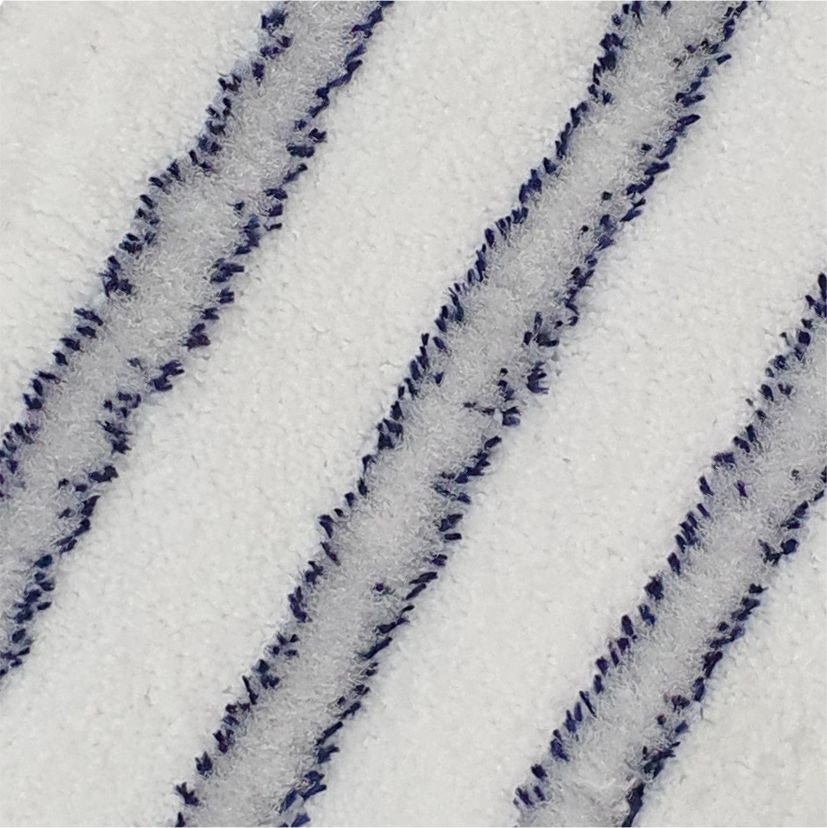 Gros plan de l'Arcora EXCELLENT SOFT MOPP BLEU-BLANC de Arcora International GmbH : sur la surface blanche texturée, trois lignes diagonales légèrement surélevées, uniformément réparties en fibres douces bleu foncé et bleu clair, assurent une finition de haute qualité.