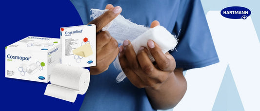 Werbebild für Hartmann Wundversorgungsprodukte. Im Vordergrund hält eine Person in blauer Kleidung eine sterile Mullbinde und wickelt diese um die Hand. Links sind Produktverpackungen von „Cosmopor steril“ (sterile Wundauflage) und „Grassolind neutral“ (Wundauflage) abgebildet, daneben eine aufgerollte Mullbinde. Oben rechts ist das Hartmann-Logo zu sehen.