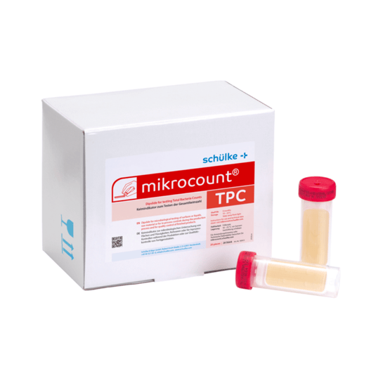 Een witte doos met het opschrift „Schülke & Mayr GmbH Mikrocount® TPC, kweekmedium | Verpakking (20 stuks)”, voorzien van een logo en een productbeschrijving, naast twee flesjes voor microbiële tests, waarvan het ene een gele dop heeft en het andere een doorzichtige dop.