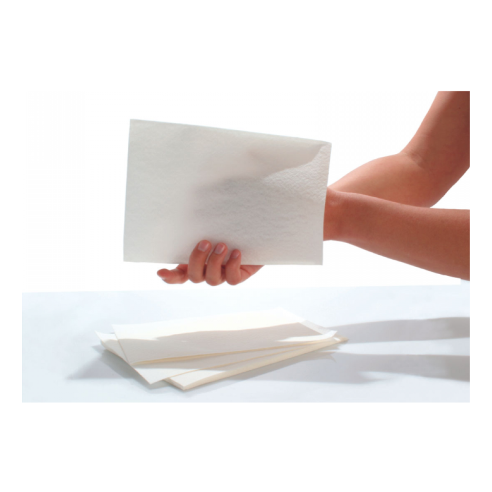 Une main tient un drap qui ressemble au matériau des gants de toilette Seni Care de TZMO Deutschland GmbH. En dessous, plusieurs draps similaires sont dispersés sur un fond blanc simple.