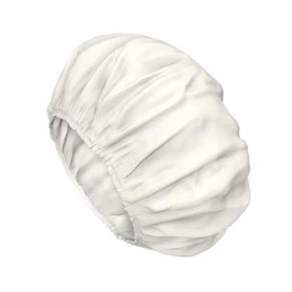 Un bonnet en satin blanc avec des bords élastiques froncés pour protéger les cheveux, rappelant le soin doux du bonnet de lavage TENA ProSkin Shampoo Cap.