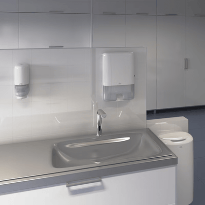 Een moderne openbare badkamer is uitgerust met een wastafel en kraan van roestvrij staal, met links een Tork 561600 huidverzorgingsdispenser met Intuition Sensor Elevation S4 voor zeep. De papieren handdoekdispenser rechts zorgt met intuïtieve contactloze dispenserfunctie voor hygiëne. De inrichting wordt voltooid door wit betegelde muren en kasten.