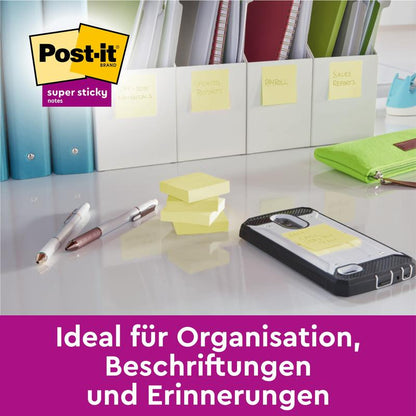 Meerdere stapels Post-it® Super Sticky Notes (47,6 mm x 47,6 mm, 90 vel/blok, 100% PEFC) van 3M Deutschland GmbH en pennen liggen op een bureau. Een tekstoverlay luidt: "Ideaal voor organisatie, labeling en herinneringen."