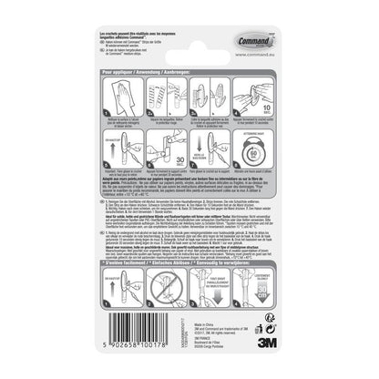 Arrière d'un emballage de crochet de designer moyen Command™, 17081-FGN de 3M Deutschland GmbH avec des instructions illustrées étape par étape pour les bandes adhésives, texte multilingue, logo 3M, site Web, code-barres et un conseil pour l'organisation domestique (Haken Aufbewahrung).