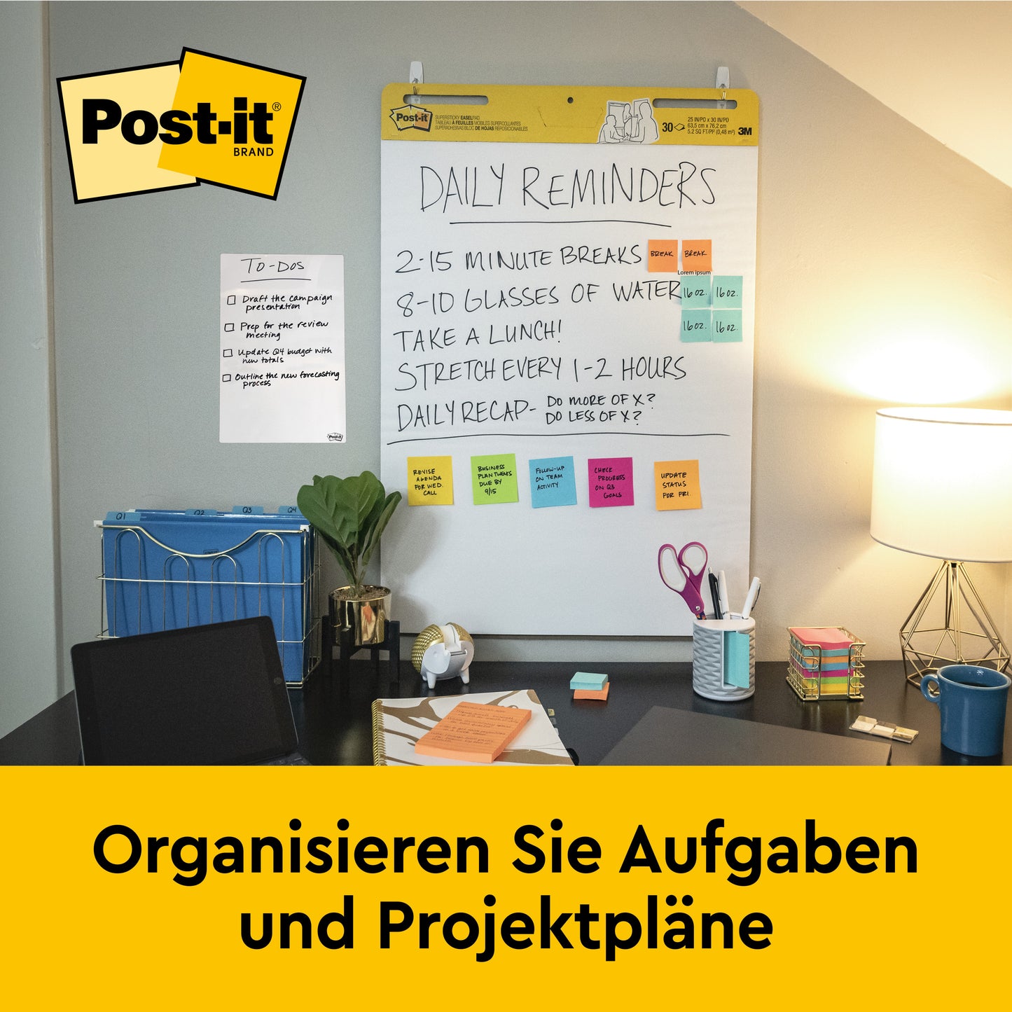 Ein Schreibtisch mit Büromaterial, Lampe und Stuhl steht vor einer an der Wand befestigten 3M Post-it® Super Sticky selbsthaftendes Meeting Chart (63,5x76,2 cm, 30 Blatt), das tägliche Erinnerungen und Notizen zeigt. Auf einem gelben Banner darunter steht "Organisieren Sie Aufgaben und Projektpläne.
