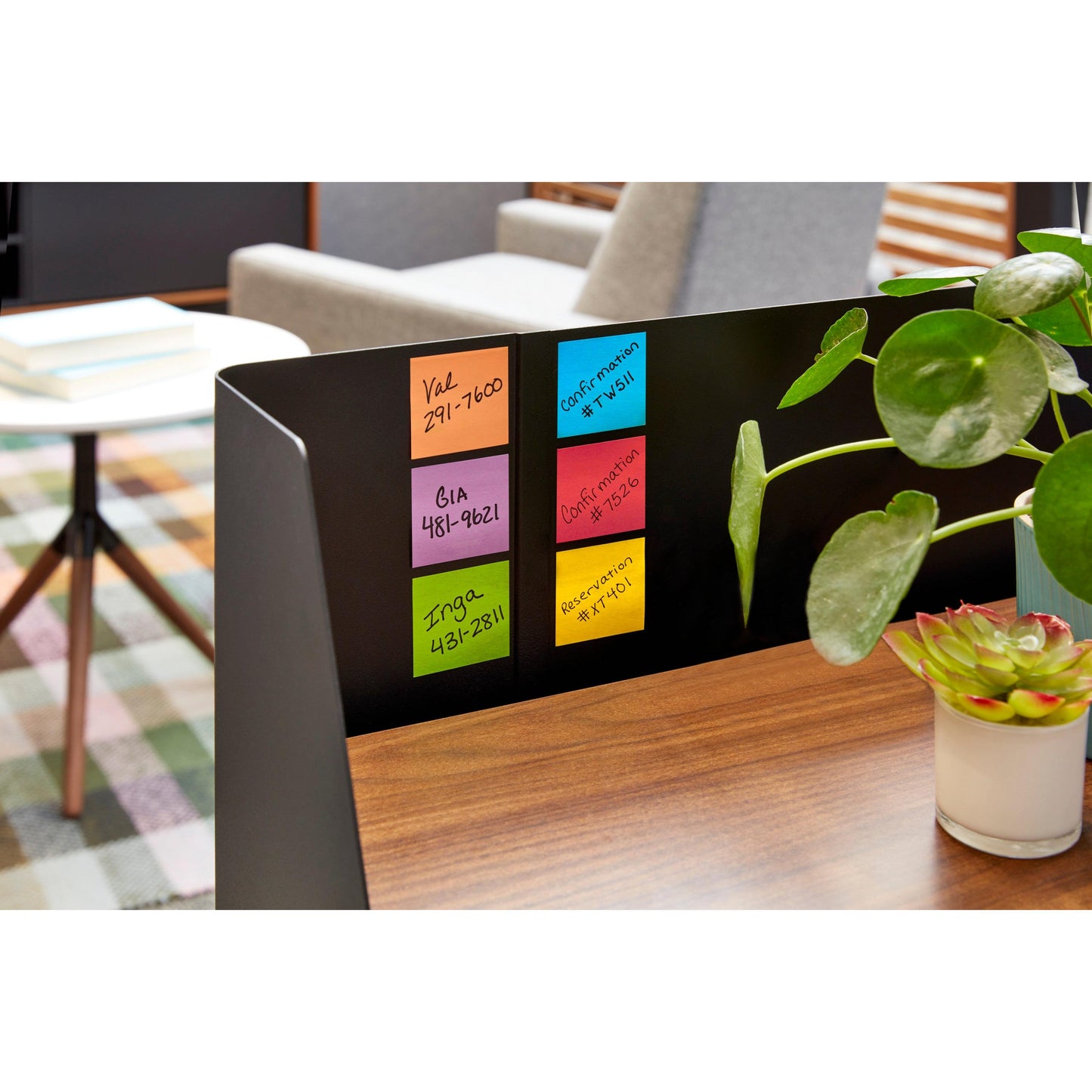 Ein weißer, katzenförmiger Post-it® Z-Notes Dispenser der 3M Deutschland GmbH hält rosa Super Sticky Z-Notes (76x76mm, 90 Blatt) auf einem Schreibtisch mit Büchern, Stühlen und einem Teppich im Hintergrund; in der Nähe steht eine grüne Topfpflanze.