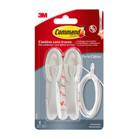 Een verpakking Command™-kabelhouders, 17304-FR van 3M Deutschland GmbH, bevat twee witte kabelhouders, plakstrips en een witte kabel in een doorzichtige kunststofverpakking – ideaal om kabelwarboel tot een minimum te beperken en de kabelorganisatie te verbeteren.