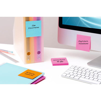 Een opgeruimd bureau met een computer, een toetsenbord, twee mappen, een notitieboek en 3M Deutschland GmbH Post-it® Super Sticky Notes (76mm x 76mm, 90 vel/blok, 100% PEFC) met Duitse herinneringen voor vergaderingen en reserveringen.