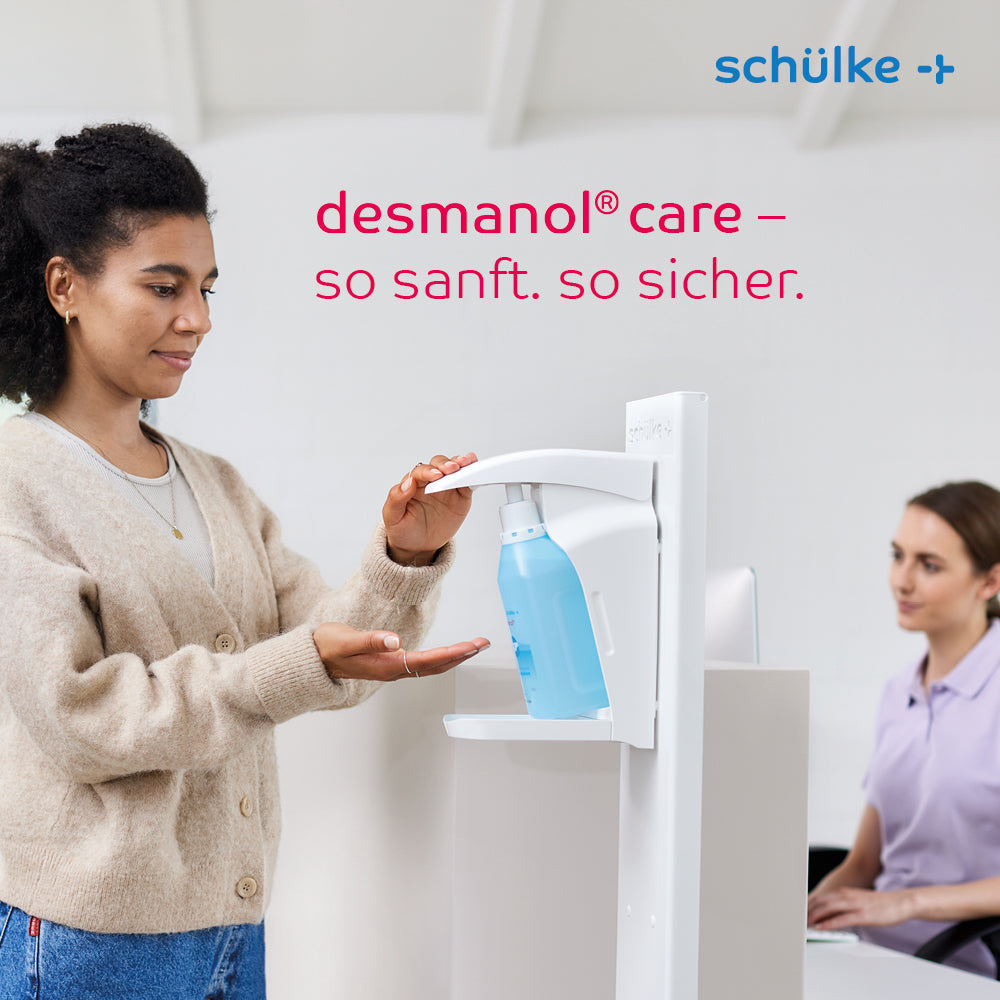 Une femme utilise un distributeur de désinfectant pour les mains Schülke desmanol® care sur un comptoir, tandis qu'une autre femme est assise à proximité et travaille sur un ordinateur. Le texte « desmanol® care – si doux. si sûr. » et la marque « Schülke & Mayr GmbH » sont présentés, mettant en avant la formule de soin de la peau pour une application douce et efficace du désinfectant pour les mains.